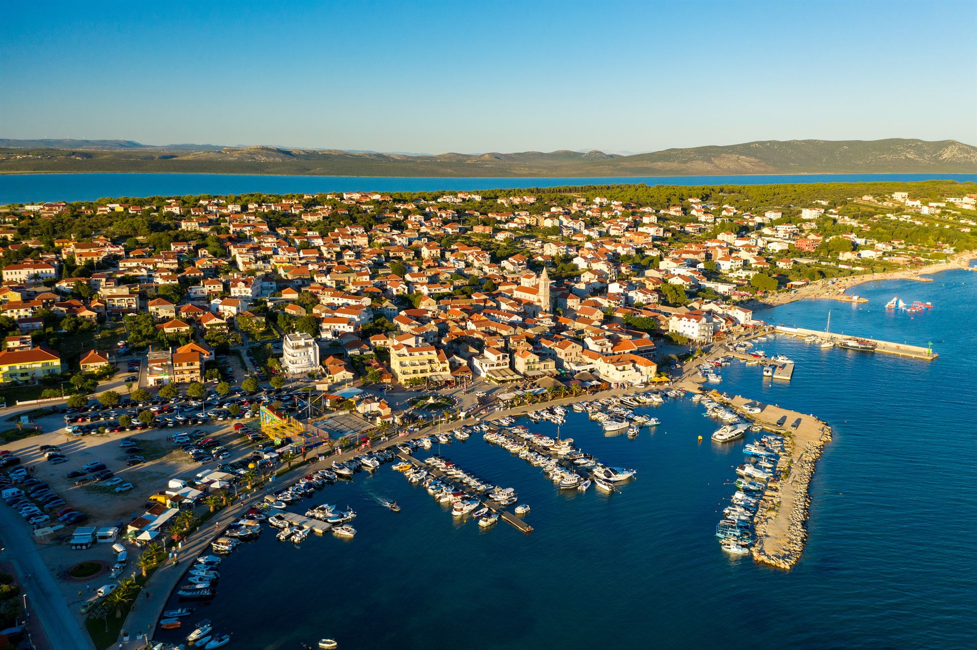 Nadmorskie miasteczko z czerwonymi dachami, zatoką i zatłoczonym portem jachtowym przy pirsie